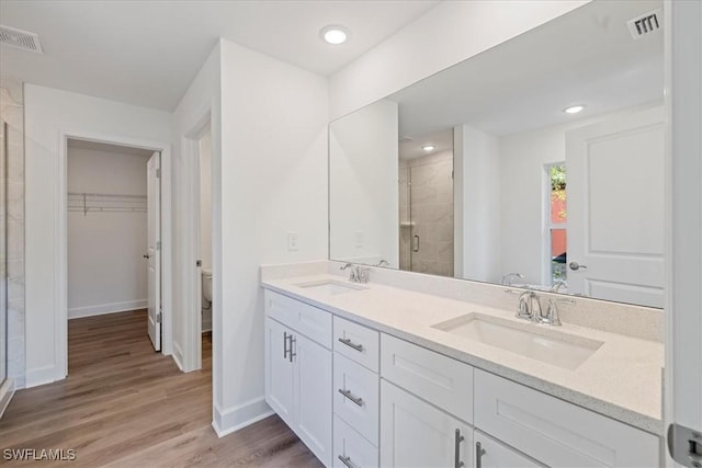 bathroom with hardwood / wood-style flooring, vanity, toilet, and a shower with door