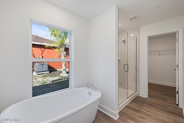 bathroom with hardwood / wood-style flooring and separate shower and tub