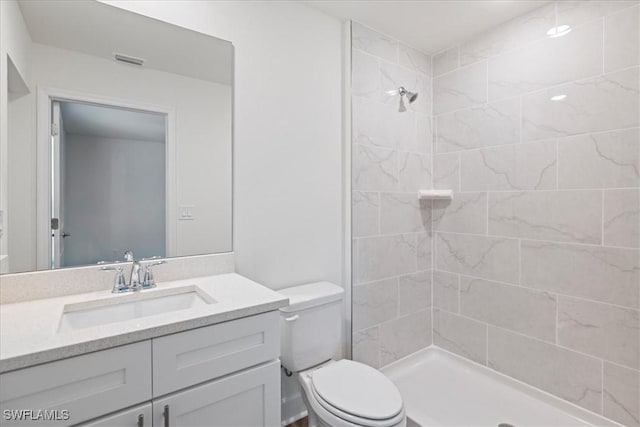 bathroom with vanity, toilet, and a tile shower