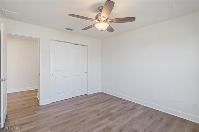 unfurnished bedroom with ceiling fan, light wood-type flooring, and a closet