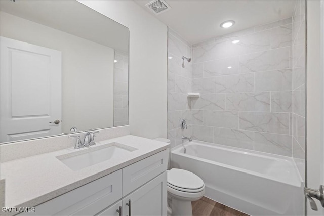 full bathroom featuring tiled shower / bath, vanity, toilet, and hardwood / wood-style floors