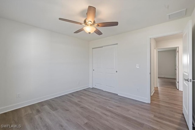 unfurnished bedroom with ceiling fan, light hardwood / wood-style floors, and a closet