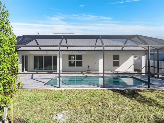 back of house featuring a patio area, glass enclosure, and a lawn