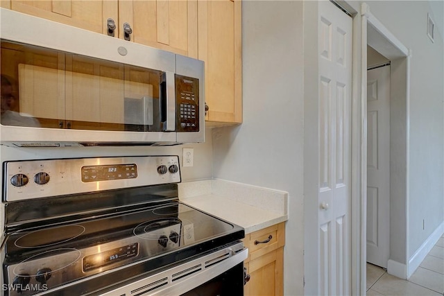 kitchen featuring stainless steel appliances, light tile patterned floors, and light brown cabinetry