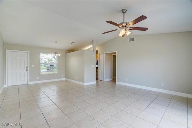 tiled empty room featuring lofted ceiling and ceiling fan with notable chandelier