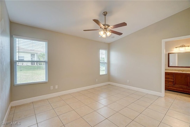 spare room featuring light tile patterned floors, vaulted ceiling, sink, and ceiling fan