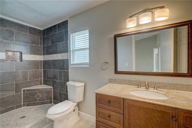 bathroom featuring vanity, a tile shower, tile patterned floors, and toilet