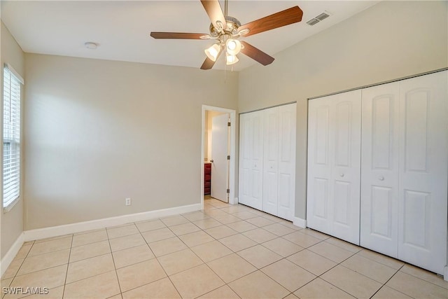 unfurnished bedroom featuring vaulted ceiling, ceiling fan, light tile patterned floors, and two closets