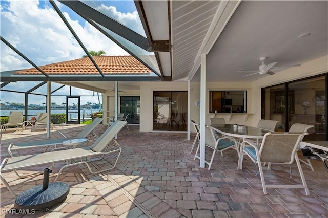 view of patio with a water view, ceiling fan, and a lanai