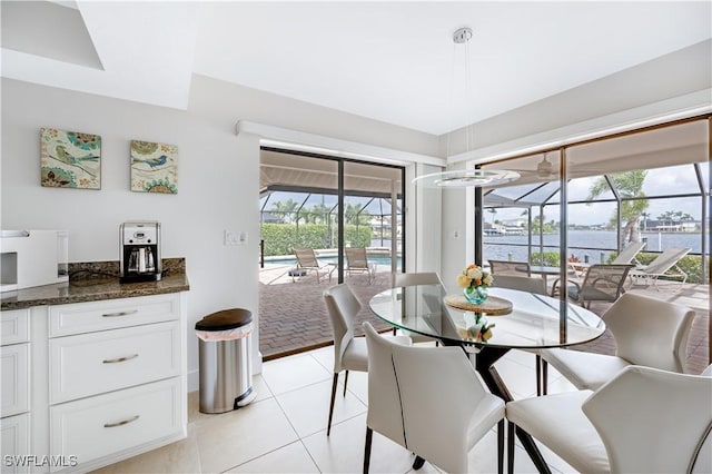 dining space featuring light tile patterned flooring and a water view