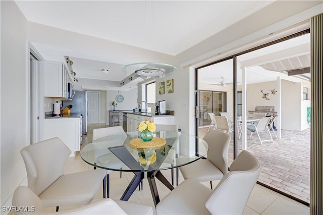 tiled dining area with ceiling fan and sink