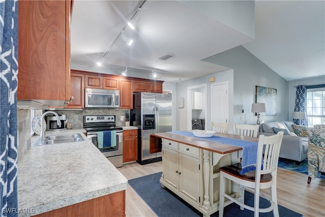 kitchen featuring sink, stainless steel appliances, a kitchen breakfast bar, tasteful backsplash, and light hardwood / wood-style floors