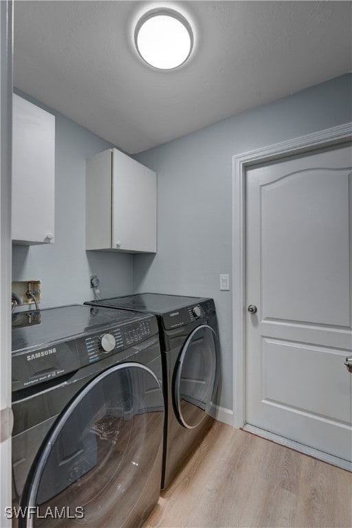 clothes washing area with independent washer and dryer, light hardwood / wood-style flooring, and cabinets