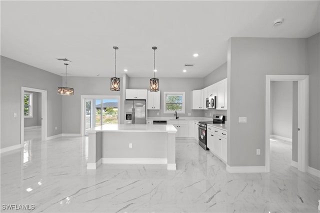 kitchen featuring sink, white cabinetry, decorative light fixtures, appliances with stainless steel finishes, and a kitchen island