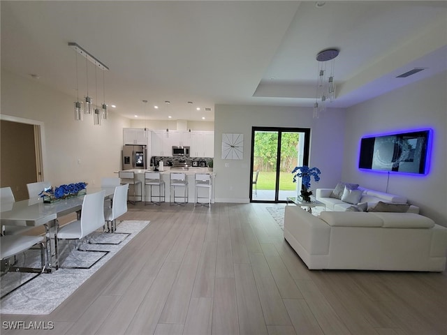 living room featuring a raised ceiling and light hardwood / wood-style flooring