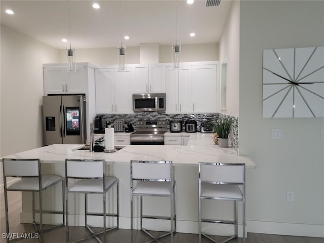 kitchen with decorative backsplash, light stone countertops, white cabinets, and appliances with stainless steel finishes