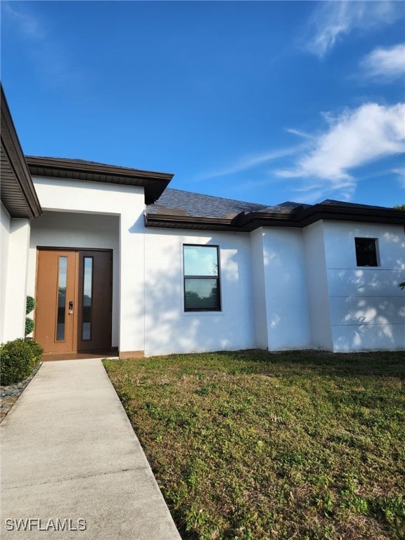 property entrance featuring a garage and a lawn