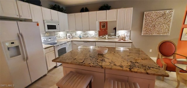 kitchen featuring white cabinetry, white appliances, a kitchen breakfast bar, and a center island