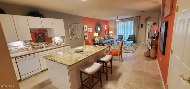 kitchen featuring tasteful backsplash, dishwasher, a kitchen island, and white cabinets