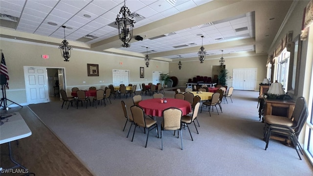 dining area with a towering ceiling, a tray ceiling, carpet floors, and a drop ceiling