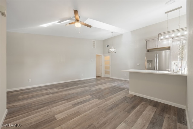 unfurnished living room with dark wood-type flooring, ceiling fan, sink, and vaulted ceiling