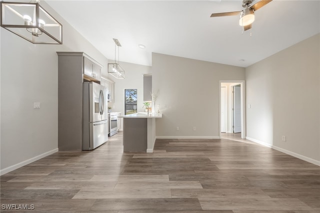 interior space with dark wood-type flooring, gray cabinets, stainless steel appliances, ceiling fan with notable chandelier, and vaulted ceiling