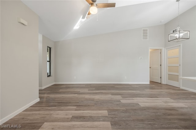 empty room with hardwood / wood-style flooring, ceiling fan with notable chandelier, and high vaulted ceiling