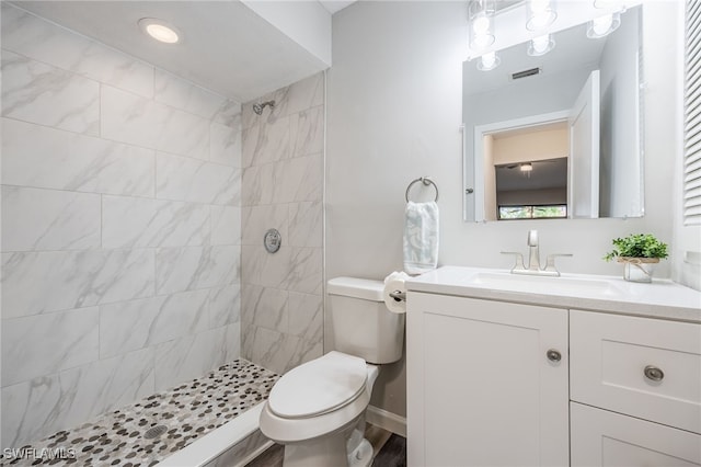 bathroom with vanity, toilet, and a tile shower