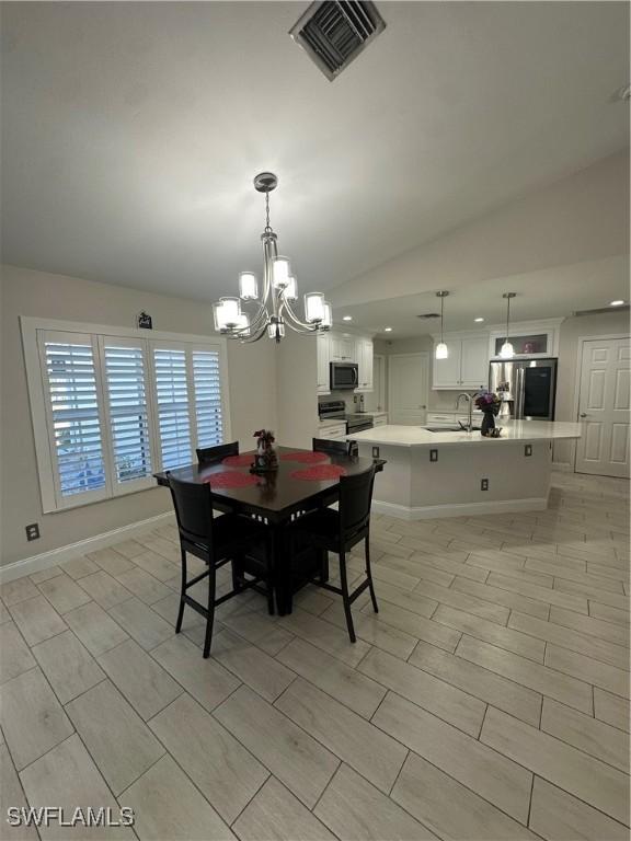 dining room with lofted ceiling, sink, and a notable chandelier