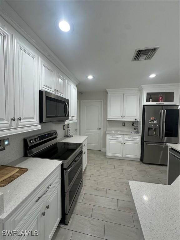 kitchen with stainless steel appliances, white cabinets, and light stone counters