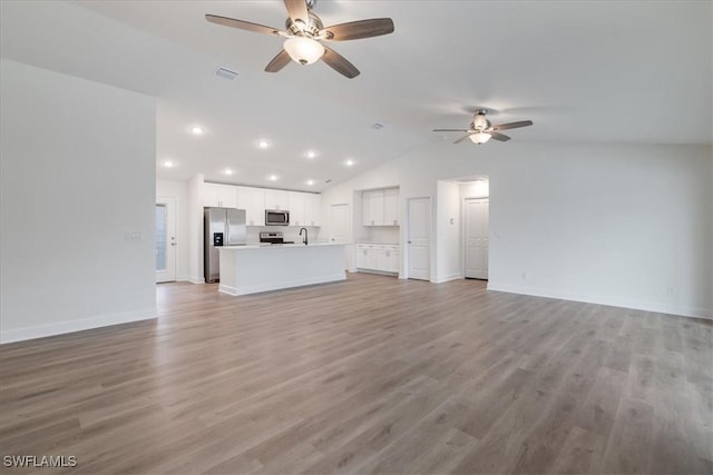 unfurnished living room featuring lofted ceiling, sink, light hardwood / wood-style floors, and ceiling fan