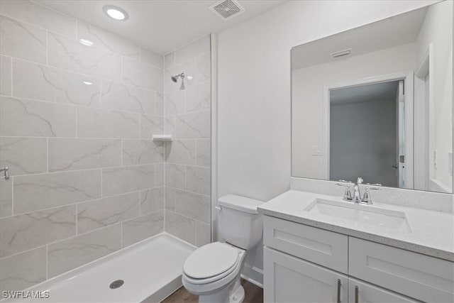 bathroom with vanity, toilet, and tiled shower