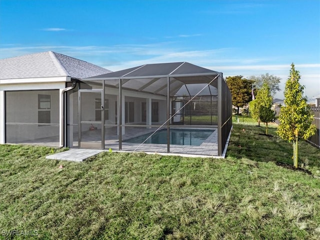 back of property with a patio area, a lawn, and glass enclosure