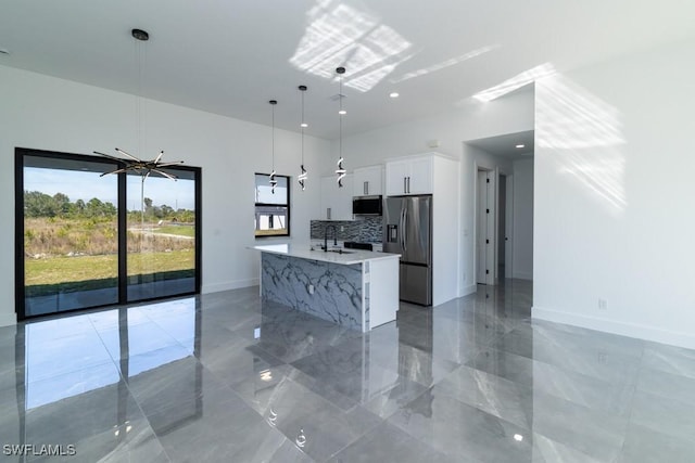 kitchen with sink, appliances with stainless steel finishes, white cabinetry, a kitchen island, and decorative light fixtures