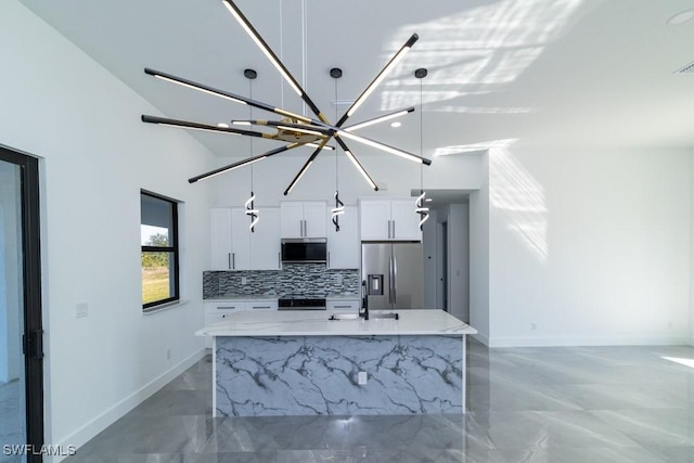 kitchen with hanging light fixtures, white cabinetry, appliances with stainless steel finishes, and an island with sink