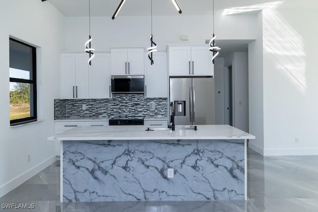 kitchen with sink, white cabinetry, hanging light fixtures, stainless steel appliances, and a center island with sink