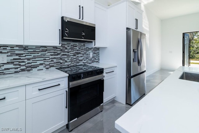 kitchen with white cabinetry, light stone counters, tasteful backsplash, stainless steel fridge, and range with electric cooktop