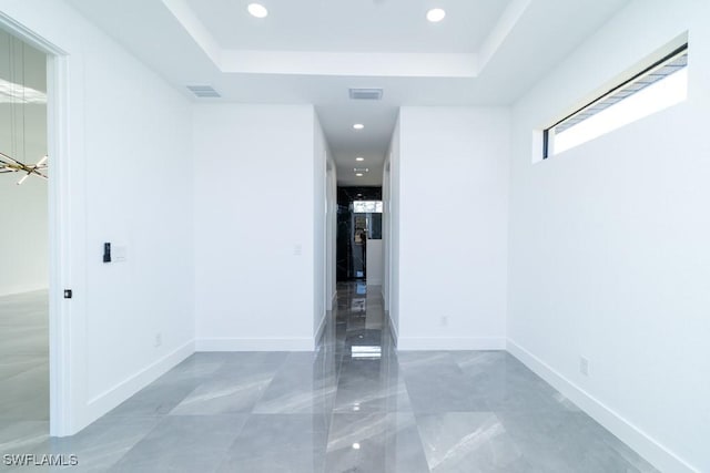 corridor with a notable chandelier and a tray ceiling