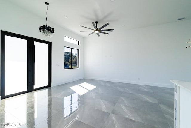 spare room with ceiling fan with notable chandelier and french doors