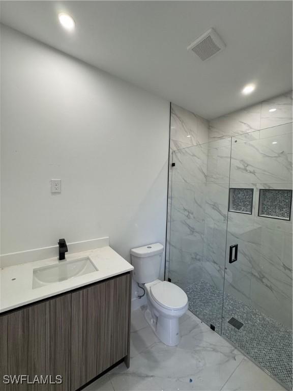 bathroom with vanity, visible vents, a marble finish shower, toilet, and marble finish floor