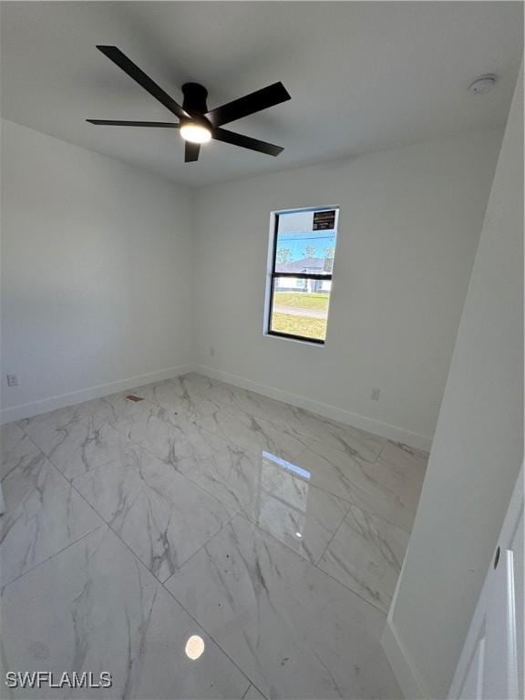 spare room featuring baseboards, marble finish floor, and ceiling fan