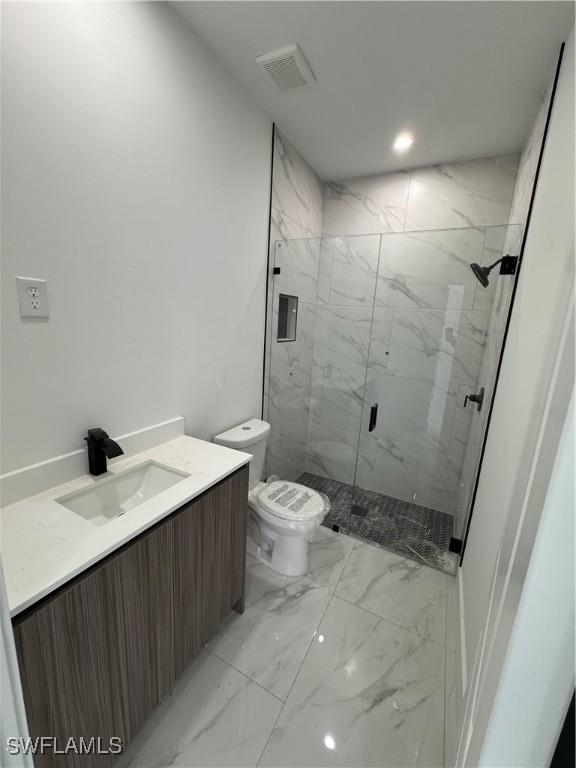 full bath featuring a marble finish shower, visible vents, toilet, marble finish floor, and vanity