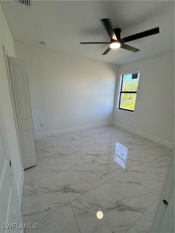 spare room featuring marble finish floor, baseboards, and ceiling fan