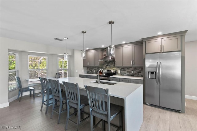 kitchen with decorative light fixtures, sink, decorative backsplash, stainless steel appliances, and wall chimney range hood