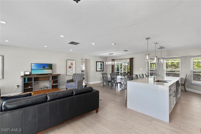 living room featuring sink, a wealth of natural light, and light hardwood / wood-style floors