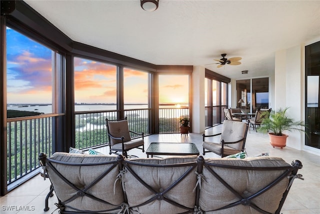 sunroom with a water view and ceiling fan