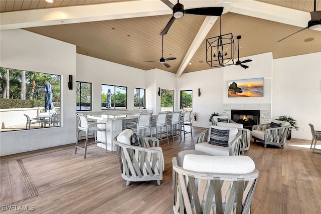 living room featuring high vaulted ceiling, wood finished floors, wood ceiling, ceiling fan, and a tile fireplace