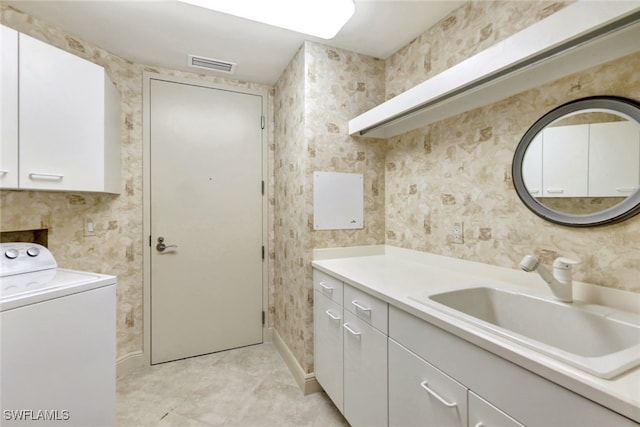 washroom featuring visible vents, a sink, cabinet space, wallpapered walls, and washer / dryer