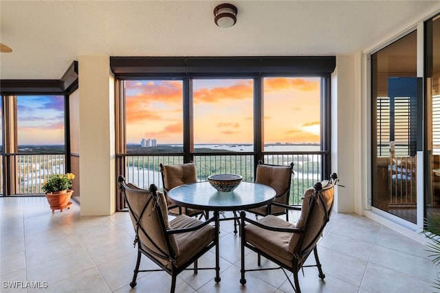 dining space featuring floor to ceiling windows, a water view, and light tile patterned flooring