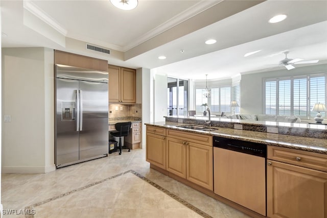 kitchen featuring sink, tasteful backsplash, dark stone countertops, ornamental molding, and stainless steel appliances